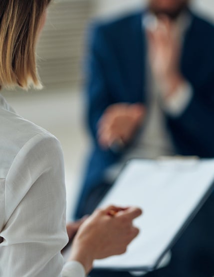A woman holding a clipboard and looking at a man